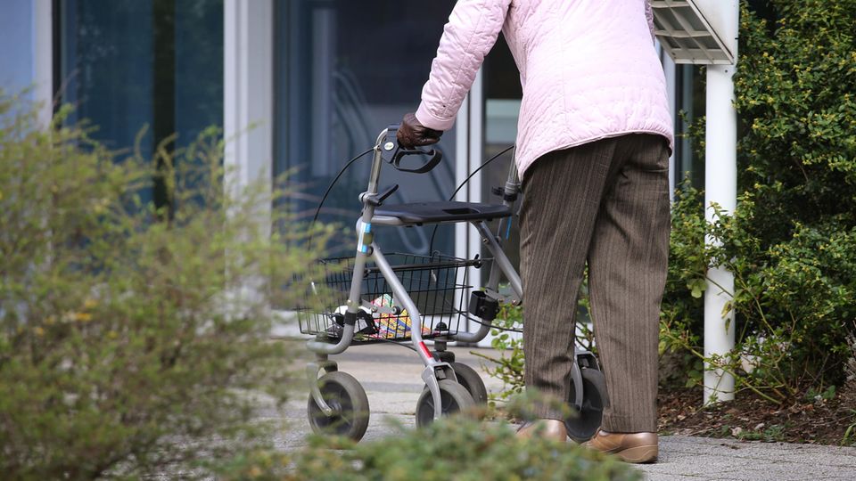 Bayern, Würzburg: Ein ältere Frau mit Rollator geht vor dem Eingang eines Senioren-Wohnstiftes