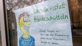 Dieses Schild mit dem Satz "Lächeln statt Händeschütteln" hängt an der Tür einer Grundschule in München