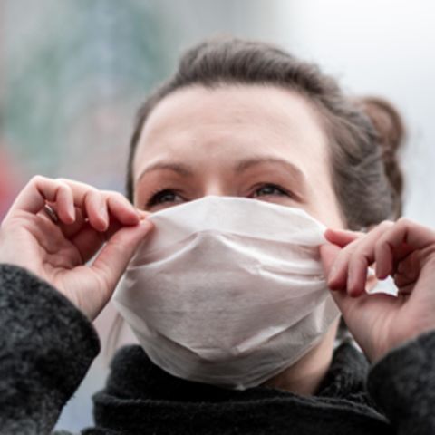 Eine Frau trägt vor einer Apotheke eine Mund- und Nasenmaske