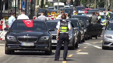 In Köln steht eine Polizistin vor den Fahrzeugen eines angehaltenen türkischen Hochzeutskorsos