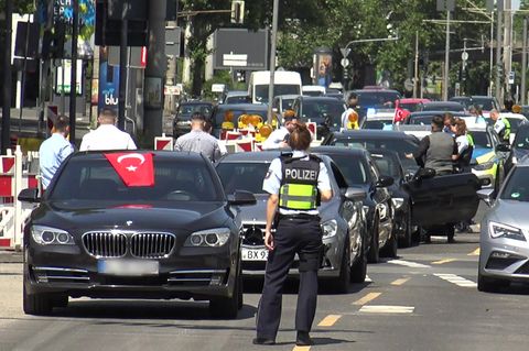 In Köln steht eine Polizistin vor den Fahrzeugen eines angehaltenen türkischen Hochzeutskorsos