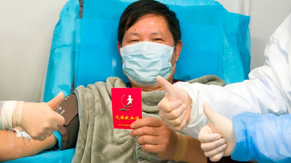 China, Wuhan: Ein genesener Coronavirus-Patient hält