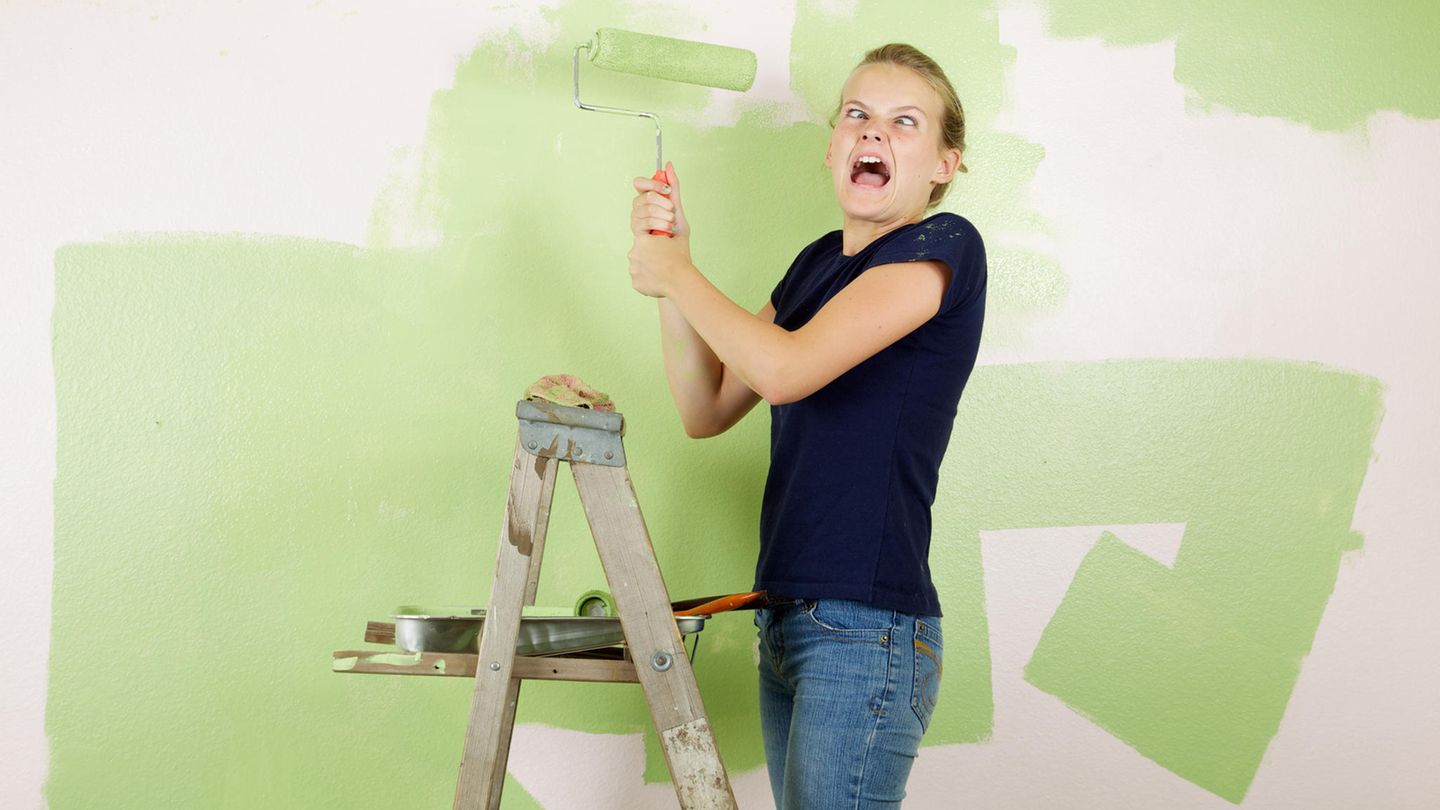 Junge Frau auf Leiter beim Streichen der Wand