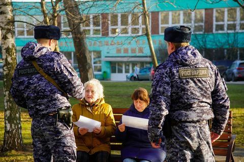 Moskau: Russische Soldaten der Nationalgarde sprechen mit zwei Rentnerinnen auf einer Parkbank.