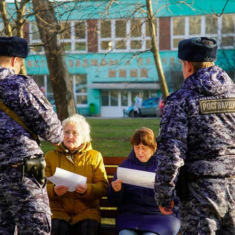 Moskau: Russische Soldaten der Nationalgarde sprechen mit zwei Rentnerinnen auf einer Parkbank.