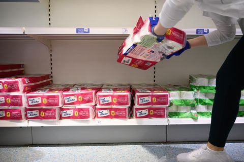 Eine Mitarbeiterin füllt leere Toilettenpapier-Regale auf