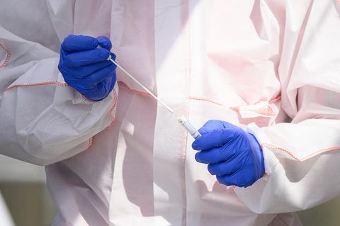 Ein Mitarbeiter hält in einem Corona-Abstrichzentrum einen Test auf das Coronavirus Sars-Cov-2 in den Händen