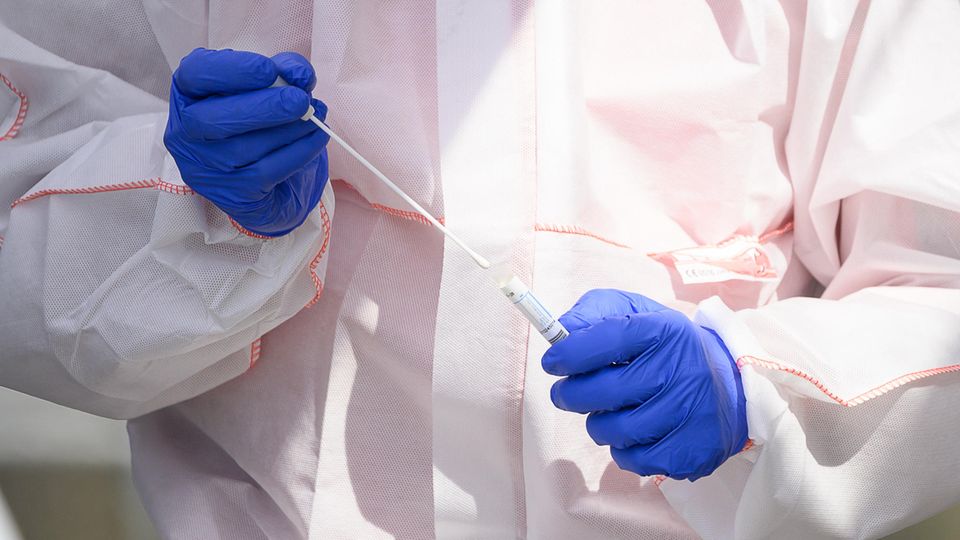 Ein Mitarbeiter hält in einem Corona-Abstrichzentrum einen Test auf das Coronavirus Sars-Cov-2 in den Händen