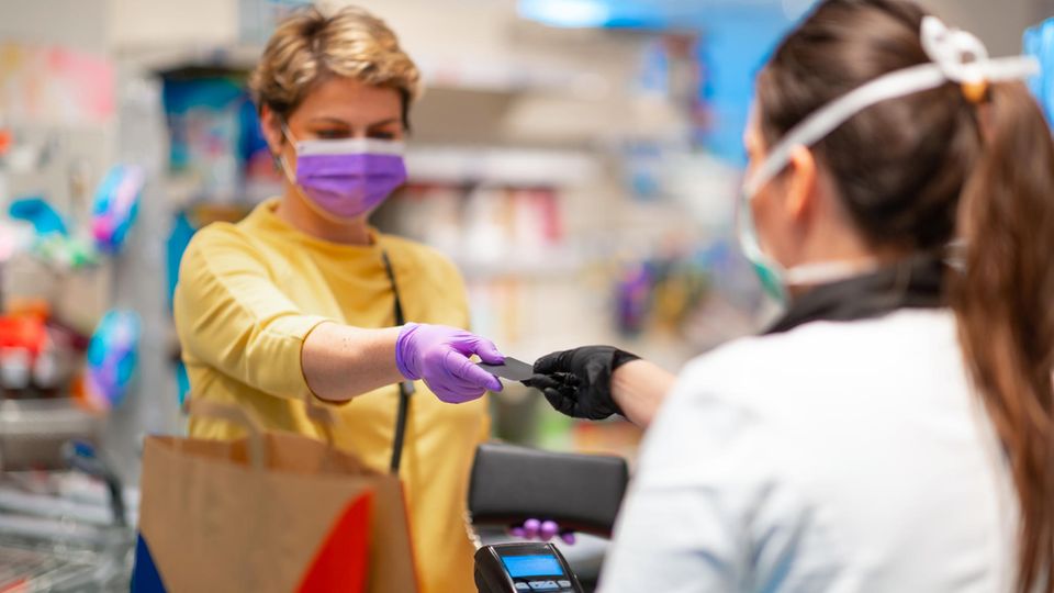 Kundin und Kassiererin tragen Schutzmasken
