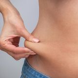 Frau kneift sich in den Bauch