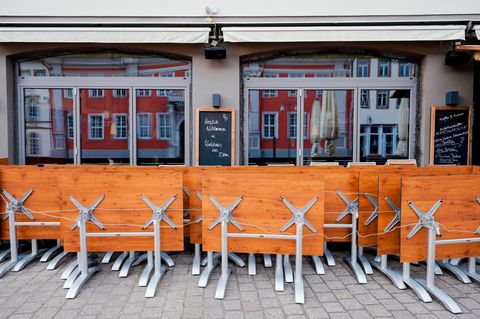 Hochgeklappte Tische stehen in der Fußgängerzone vor einer Gastwirtschaft.