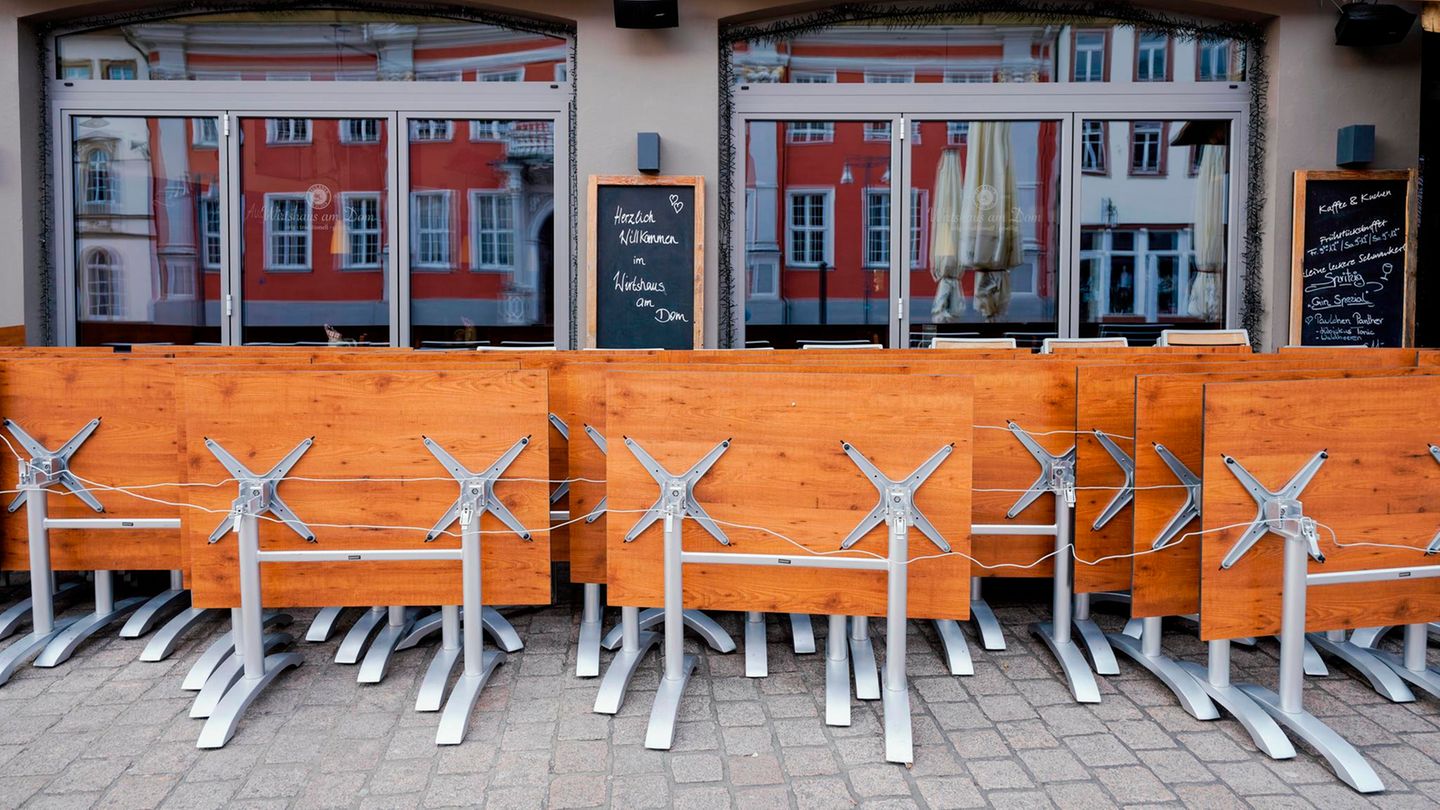 Hochgeklappte Tische stehen in der Fußgängerzone vor einer Gastwirtschaft.
