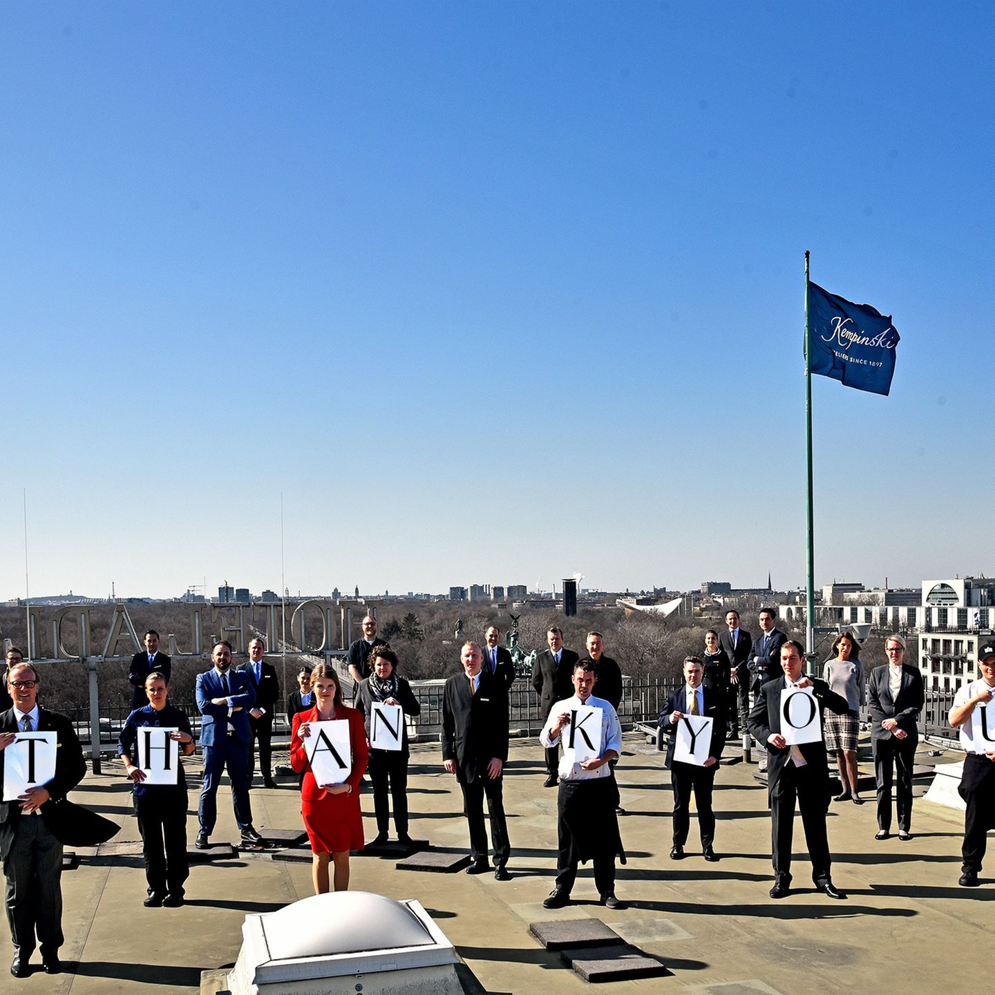Mitarbeiter auf dem Dach des Adlon Hotels in Berlin: ein Dankeschön für Krisenhelfer