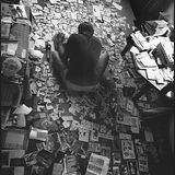 Der Fotograf sitzt zwischen Fotos und Zeitungsschnipseln