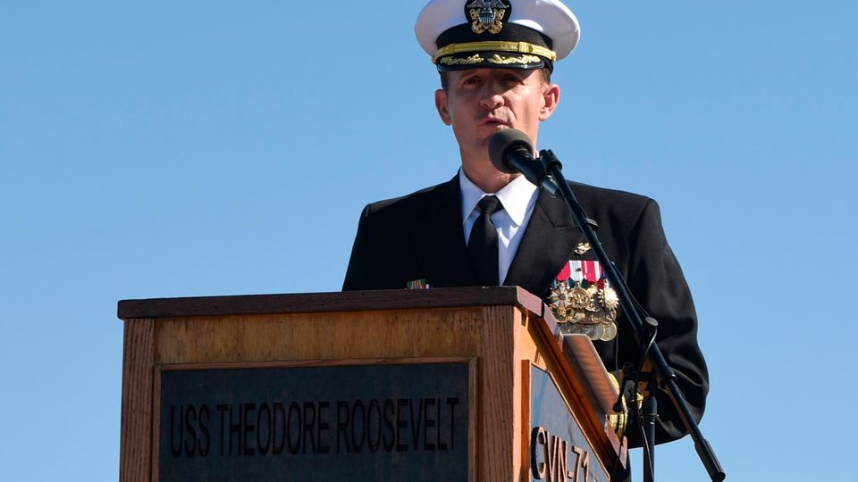 Kapitän Brett Crozier spricht im Freien an einem Rednerpult auf der "USS Theodore Roosevelt" Kapitän Brett Crozier spricht im Freien an einem Rednerpult auf der "USS Theodore Roosevelt"
