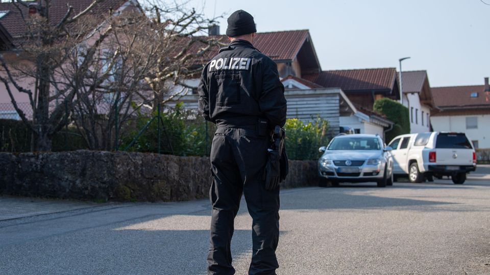 Ein Polizist steht auf der Straße vor dem Haus in Vogtareuth, in dem drei Tote Menschen aufgefunden worden waren