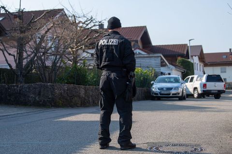 Ein Polizist steht auf der Straße vor dem Haus in Vogtareuth, in dem drei Tote Menschen aufgefunden worden waren