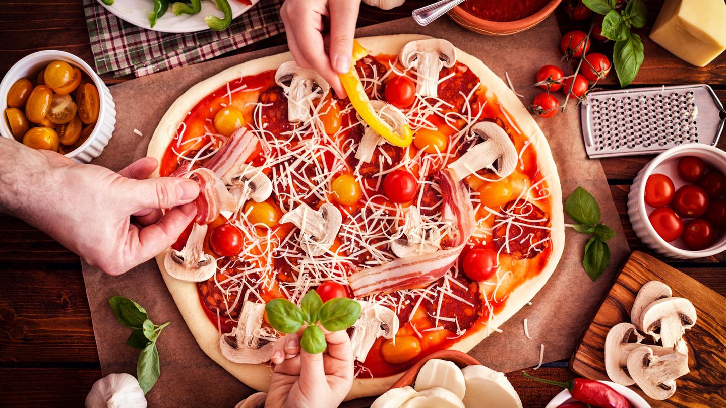 Eine Pizza wird mit Gemüse belegt