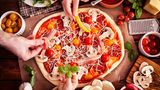 Eine Pizza wird mit Gemüse belegt