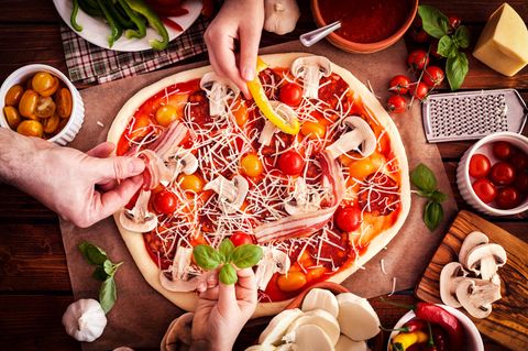 Eine Pizza wird mit Gemüse belegt