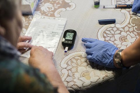 Eine ambulante Pflegerin hilf einer alten Frau ihre Diabetes-Werte zu kontrollieren