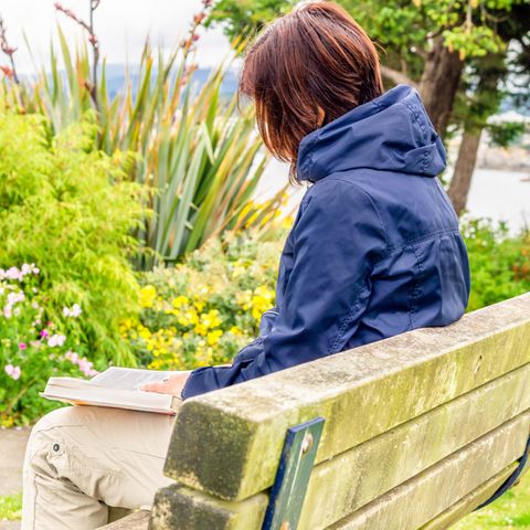 Eine Frau liest ein Buch auf einer Parkbank