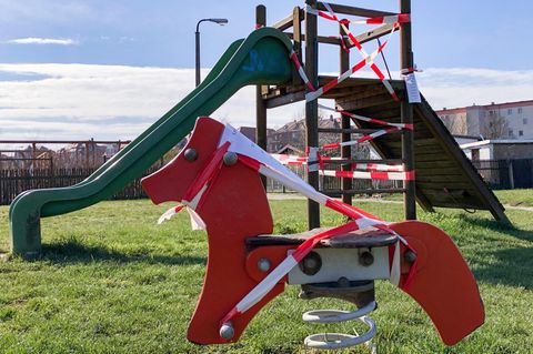 Ein rotes Spielpferd auf einer Spirale und eine grüne Rutsche im Hintergrund sind mit Absperrband umwickelt