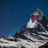 Auf das Weiß der noch vom Schnee bedeckten Ostwand wird ein rotes Herz projeziert...
