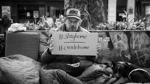 Ein Obdachloser hält ein Plakat