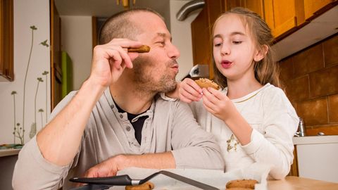 Vater und Tochter essen selbst gebackene Kekse