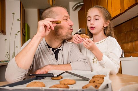 Vater und Tochter essen selbst gebackene Kekse