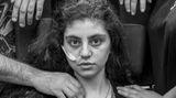 Gewinner in der Kategorie "Porträt": Ewa, ein 15-jähriges armenisches Mädchen, das kürzlich aus einem durch das Resignationssyndrom verursachten katatonischen Zustand erwacht ist, sitzt in einem Flüchtlingsaufnahmezentrum in einem Rollstuhl, flankiert von ihren Eltern. Titel des Fotos: "Awakening". 
