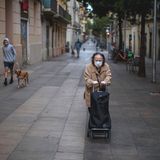 Eine einsame Frau in Barcelona schiebt ihren Wagen mit Besorgungen durch eine Gasse im Viertel Poble Sec.