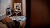 Leopoldo Roman liegt im Bett und trägt eine Gesichtsmaske, während er auf den Hausbesuch eines Arztes wartet. Roman, dessen Bein vor Jahren amputiert wurde, muss die tägliche Pflege aus seiner Rente bezahlen, da das öffentliche System nur vorsieht, dass ein Sozialarbeiter an drei Tagen in der Woche für eine Stunde am Tag kommt.