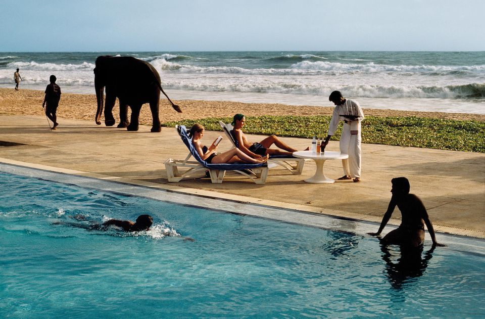 Menschen und ein Elefant zwischen Pool und Meer