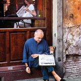 Ein Hund liest gemeinsam mit einem Mann die Tageszeitung