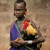 Eine junge Afrikanerin hält einen Hahn im Arm