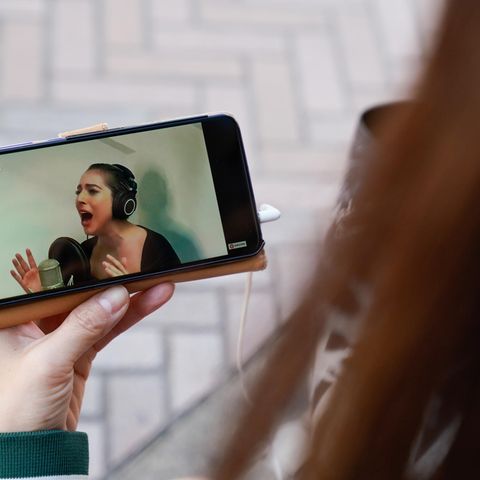 Die Japanerin Noemi sieht auf ihrem Smartphone die Live-Stream-Performance von Lady Gaga.