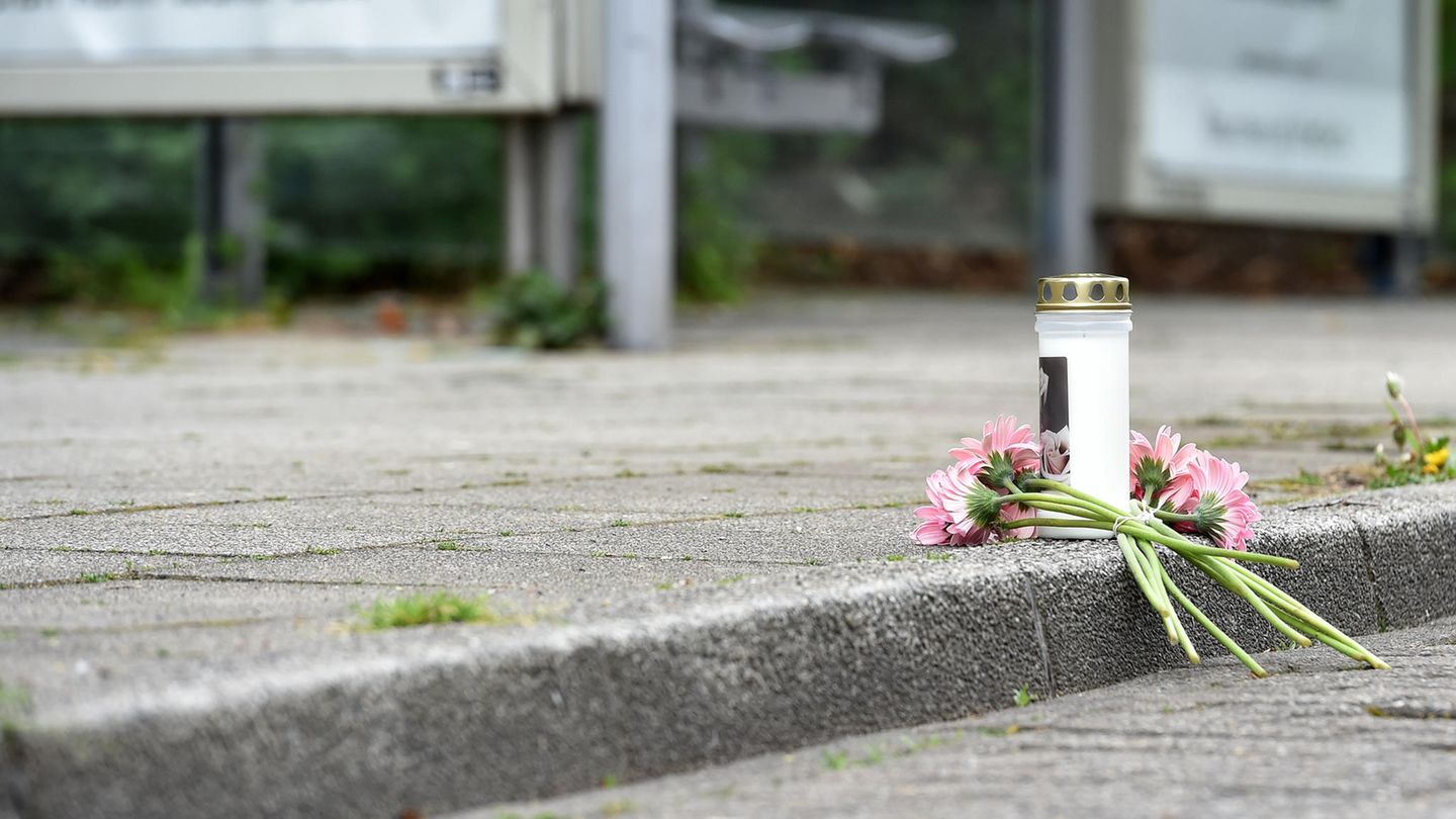 Eine Kerze und Blumen liegen an einer Haltestelle an der in der Nacht ein 14 Jahre alter Junge erstochen wurde.