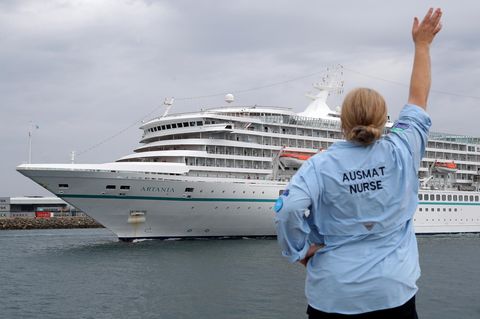 Eine Mitarbeiterin des Australian Medical Assistance Teams (AUSMAT), die mit den Passagieren und der Besatzung des Kreuzfahrtschiffes MV Artania gearbeitet haben, winkt zum Abschied, als das Schiff den Hafen von Fremantle verlässt.