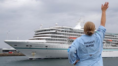 Eine Mitarbeiterin des Australian Medical Assistance Teams (AUSMAT), die mit den Passagieren und der Besatzung des Kreuzfahrtschiffes MV Artania gearbeitet haben, winkt zum Abschied, als das Schiff den Hafen von Fremantle verlässt.