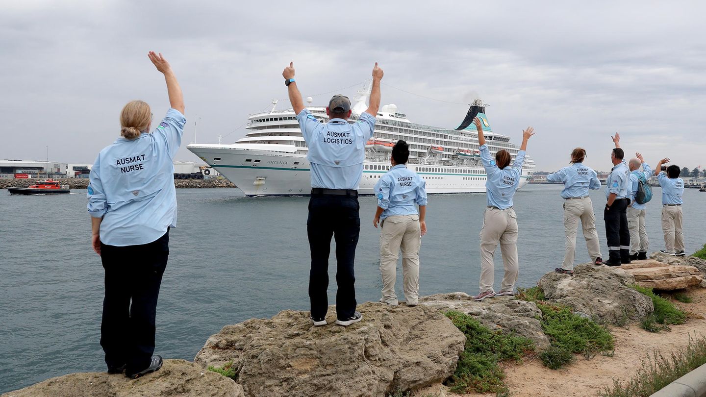 Mitarbeiter des Australian Medical Assistance Teams (AUSMAT), die mit den Passagieren und der Besatzung des Kreuzfahrtschiffes "MS Artania" gearbeitet haben, winken zum Abschied, als das Schiff den Hafen von Fremantle verlässt.