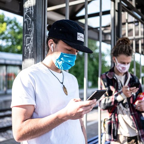 Zwei Personen mit Mundschutz am Handy
