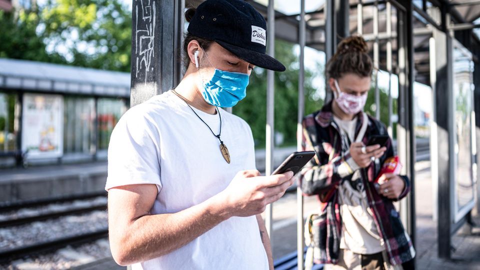 Zwei Personen mit Mundschutz am Handy