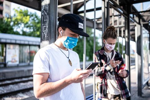 Zwei Personen mit Mundschutz am Handy