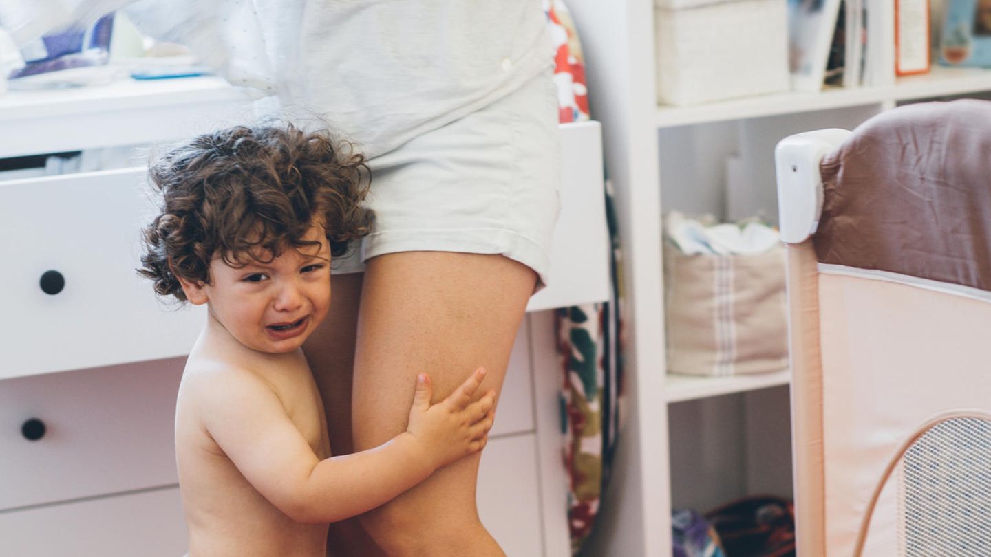 Ein Kleinkind weint neben seiner Mutter