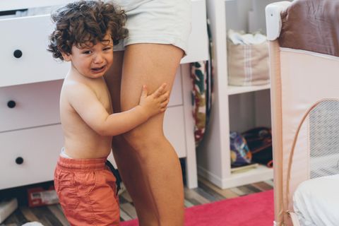 Ein Kleinkind weint neben seiner Mutter