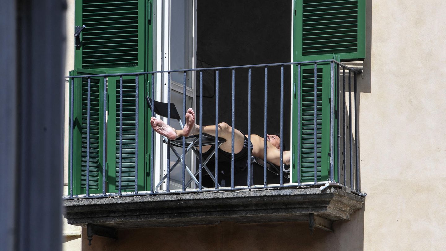 Ein Mann sonnt sich auf einem Balkon in Neapel. Seine Füße ragen durch das Gitter. Ein Mann sonnt sich auf einem Balkon in Neapel. Seine Füße ragen durch das Gitter.