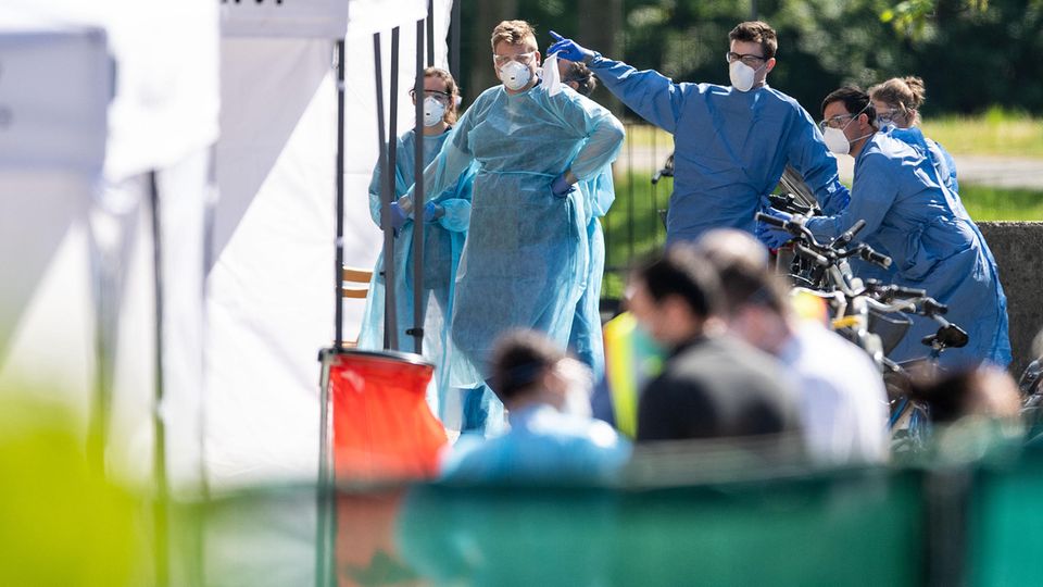 Mitarbeiter vom Gesundheitsamt warten an den Zelten, vor einem Wohnkomplex, darauf, Corona-Tests durchzuführen Mitarbeiter vom Gesundheitsamt warten an den Zelten, vor einem Wohnkomplex, darauf, Corona-Tests durchzuführen
