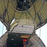 Die geöffnete Bugklappe von unten: Auf der Leiter klettert eine Dame in roter Jacke aufwärts...